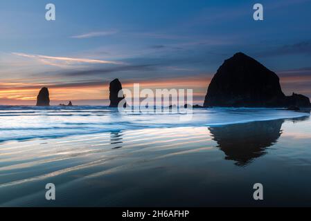 Wellen vor dem Cannon Beach Heuhaufen zur blauen Stunde Stockfoto
