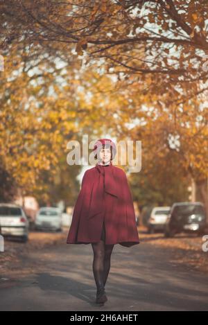 Junge Frau in roten Retro-Vintage-Kleidung, die die Straße entlang geht Stockfoto