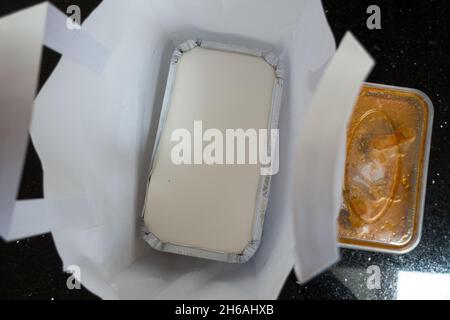 Draufsicht auf einen Beutel zum Mitnehmen von Lebensmitteln mit Behälter aus Aluminiumfolie, der sich unten im Beutel befindet Stockfoto