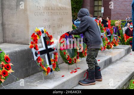 Nach der Zeremonie zum Gedenktag 2021 legen die Menschen ihre Mohnblumen ab und zollen dem Kenotaph ihren Respekt. Cambridge, Ontario, Kanada. Stockfoto