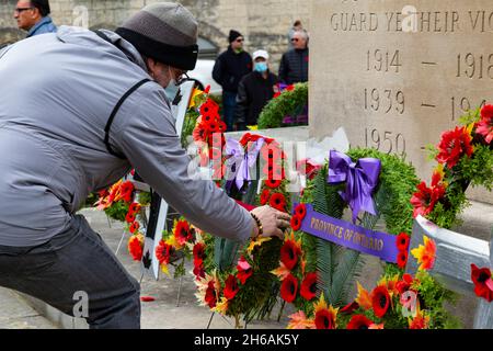 Nach der Zeremonie zum Gedenktag 2021 legen die Menschen ihre Mohnblumen ab und zollen dem Kenotaph ihren Respekt. Cambridge, Ontario, Kanada. Stockfoto