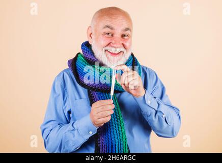 Lächelnder bärtiger Mann im Schal mit Thermometer. Medizin, Behandlungen und Gesundheitskonzept. Stockfoto