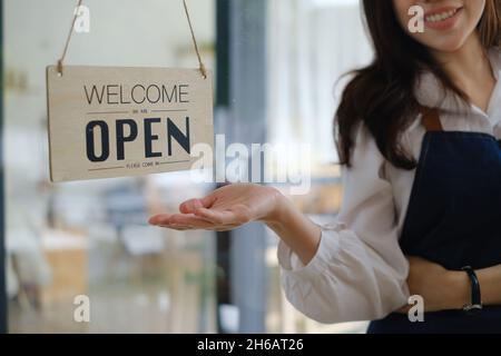 Frau Besitzerin mit Lächeln drehen ein Zeichen von geschlossen zu öffnen. kmu-Konzept Stockfoto
