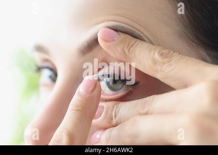 Frau zieht aus der Nähe weiche Kontaktlinsen an Stockfoto