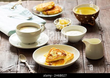 Frühstück mit Käsekuchen, Kaffee und Tee. Käsekuchen von einer ungewöhnlichen dreieckigen Form. Stockfoto