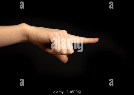 Hand zeigt auf etwas. Frau Handbewegung, zeigendes Zeichen, Geste Schauen Sie sich das an, Pass auf. Schwarzer Hintergrund Stockfoto