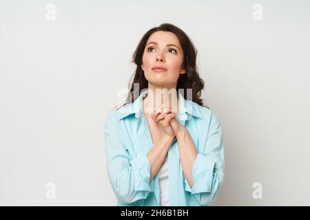 Brünette Frau faltete ihre Hände im Gebet. Eine Frau bittet Gott um Hilfe Stockfoto