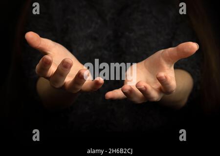 Betende Geste mit Händen auf schwarzem Hintergrund Stockfoto