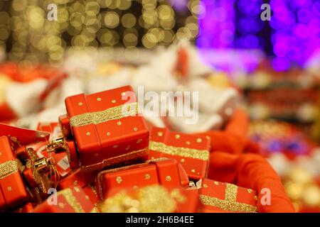Weihnachtsspielzeug, rote Geschenkschachteln in einem Korb. Neujahrsdekoration in einem Geschäft auf unscharfem festlichem Hintergrund Stockfoto