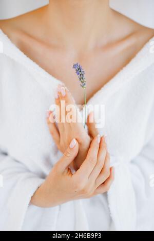 Mädchen in einer weißen Robe hält eine Lavendelblume vor sich. Nahaufnahme Stockfoto