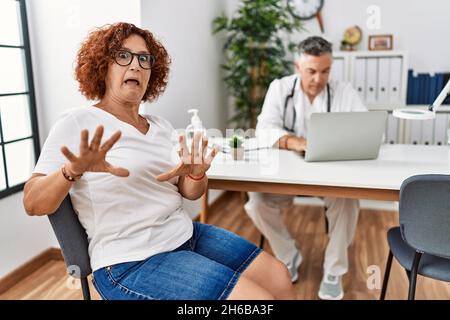 Ältere Frau sitzt bei Arzttermin Angst und erschrocken vor Angst Ausdruck Stop Geste mit den Händen, schreiend in Schock. Panik Konzept. Stockfoto