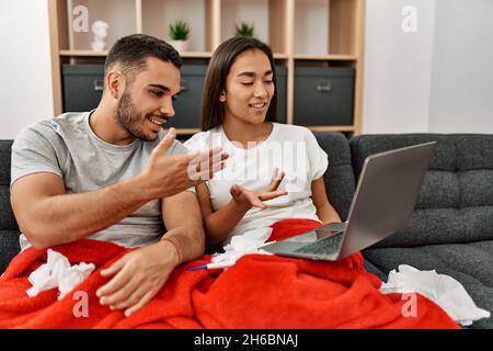 Junge lateinamerikanische kranke Paare, die zu Hause eine medizinische Fernsulation mit einem Laptop haben. Stockfoto