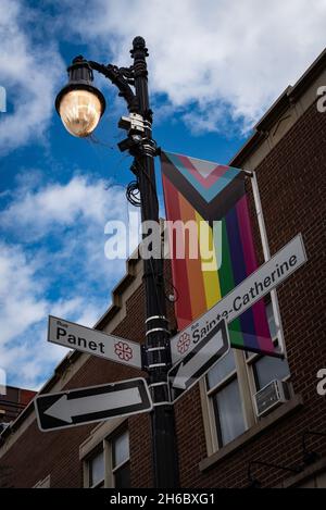 MONTREAL, QC, KANADA - ÜLG. 1, 2021: Foto einer Hauptkreuzung im Stadtteil Gay Village mit Progress Pride-Flagge und Lampost. Stockfoto