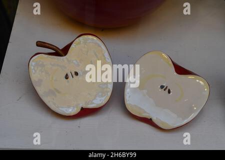 Nahaufnahme von Keramikskulpturen, die einen von Nadia Allario in zwei Hälften geschnittenen Apfel darstellen, im Schaufenster der Kunstgalerie Arte è Kaos, Alassio, Savona Stockfoto