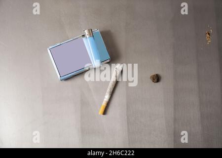 Rollende Zigaretten mit Feuerzeug, Päckchen und anderen Dingen auf grauem Tisch Stockfoto