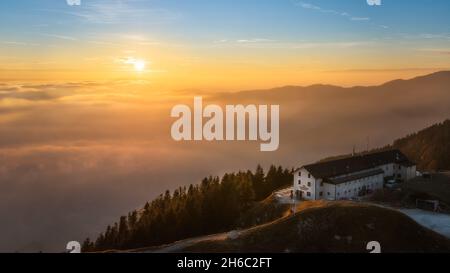 Panoramablick auf die Hütte Vittorio Veneto auf dem Gipfel des Pizzoc (Provinz Treviso, venetien, italien) gegen Wolken bei Sonnenuntergang im Herbst Stockfoto