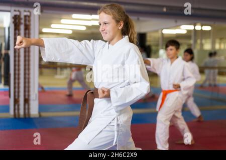 Mädchen in Kimono posiert während Karate-Gruppentraining Stockfoto