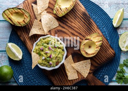 Blick von oben auf ein Gericht aus frisch zubereiteter Guacamole, umgeben von Tortilla-Chips. Stockfoto