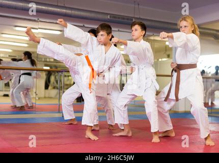 Kinder im Kimono führen Kampfbewegungen im Fitnessstudio durch Stockfoto