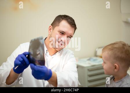 Der Zahnarzt zeigt dem kleinen Patienten ein Bild von den Zähnen. Hochwertige Fotos Stockfoto