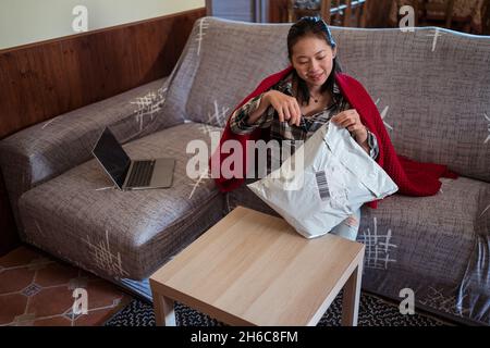 Nahaufnahme einer ostasiatischen Frau, die glücklich ein Paket öffnet Stockfoto
