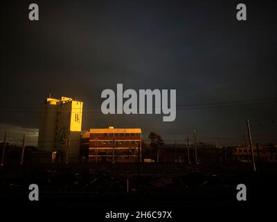 Eine Fabrik in einem Industriegebiet von Melbourne gegenüber einer Bahnlinie, beleuchtet durch den goldenen Sonnenuntergang während der Golden Hour in West Footscray, Australien. Stockfoto