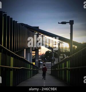 Ein Kind in einer roten Jacke läuft am leeren Bahnhof West Footscray in Melbourne, Australien, im August 2021, eine Rampe hinunter. Stockfoto