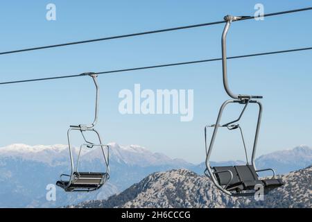 Gondelsitze aus nächster Nähe mit Schneebergen im Hintergrund. Stockfoto