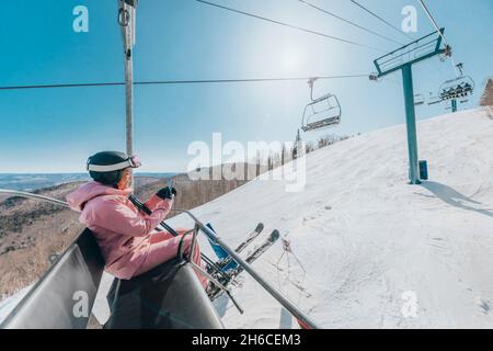 Skiurlaub - Frau Skifahrer mit Telefon im Skilift. Ski Winterurlaub Konzept. Skifahren auf Schneehängen in den Bergen, Menschen Spaß an verschneiten Tag Stockfoto