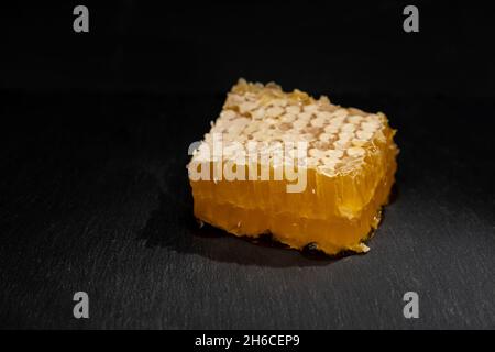Süßes Stück Honig in Kämmen Nahaufnahme auf schwarzem Hintergrund. Bio-Produktthema Stockfoto