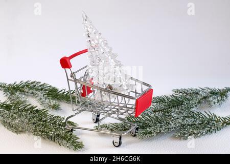 Neujahr und Weihnachten Konzept der Weihnachtsdekoration. Kleiner dekorativer Weihnachtsbaum aus klarem Glas im Warenkorb. Urlaub einkaufen, Vorbereitung für c Stockfoto