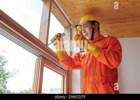 Bauarbeiter mit Hammer und Meißel entfernen alten hölzernen Fensterrahmen Stockfoto