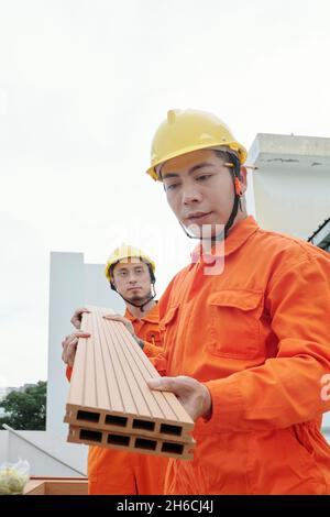 Bauarbeiter, die Holzfußböden auf das Dach des Gebäudes tragen, um den Loungebereich zu sanieren Stockfoto