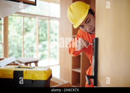Arbeiter, der intelligente elektronische Türverriegelung in der Wohnung des Kunden installiert Stockfoto