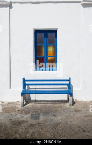 Bank unter dem Fenster gegen weiß getünchte Wand in Griechenland. Stockfoto