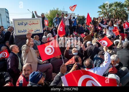 Tunis, Tunesien, 14. November 2021. Demonstranten tragen Fahnen und Plakate während eines Protestes gegen die Beschlagnahme der Regierungsgewalt durch den tunesischen Präsidenten Kais Saied am 14. November 2021 vor dem parlament in Tunis, Tunesien. Die tunesische Polizei hat in der Nähe der Kammer des suspendierten parlaments mit Demonstranten zusammengestürzt, als Demonstranten gegen die Machtergreifung von Präsident Kais Saied vor vier Monaten marschierten. Hunderte von Polizisten hatten das Gebiet, in dem sich am Sonntag Tausende von Demonstranten versammelten, blockiert, um Saied zur Wiederherstellung des parlaments und der normalen demokratischen Herrschaft aufzufordern. „Herunterfahren Stockfoto