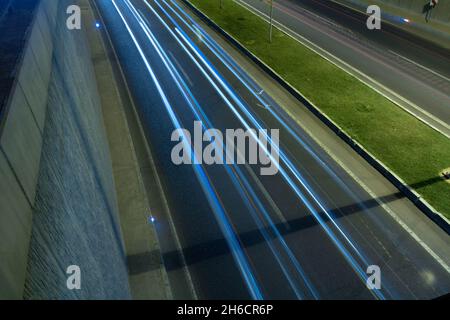 Nachts leichte Wege auf der Unterführung. Hintergrundfoto von Verkehr oder Autobahn. Zweispurige Straße und leichte Spuren von Autos. Stockfoto
