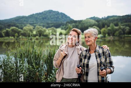 Glückliche ältere Mutter umarmt mit erwachsenen Tochter, wenn sie am See im Freien in der Natur steht Stockfoto
