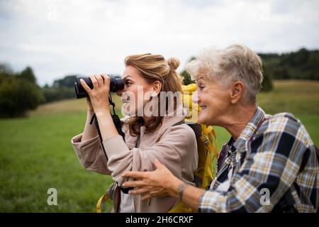 Glückliche ältere Mutter Wanderer mit erwachsenen Tochter Blick durch Ferngläser im Freien in der Natur Stockfoto