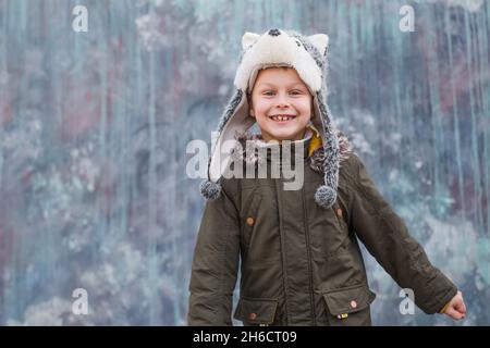 Portrait Kind in einem Wolf Hut und lächelt süß auf grauem Hintergrund, im Freien. Platz für Text. Hochwertige Fotos Stockfoto