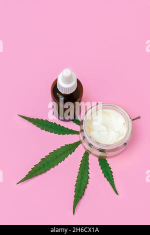 CBD Hanf Creme und Serum oder Öl mit Marihuanablatt auf rosa Hintergrund, vertikales Bild Stockfoto