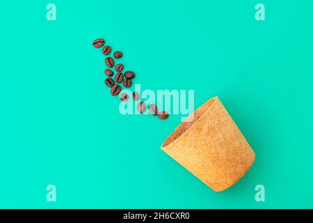 Draufsicht auf Waffelbecher mit Kaffeebohnen auf grünem Hintergrund. Zero Waste Konzept Stockfoto