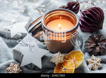 Adventsdekoration und Geschenkschachteln mit brennenden Kerzen. Weihnachten Hintergrund Stockfoto