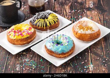 Köstliche Donuts mit verschiedenen Dekorationen auf Holztisch dekoriert Stockfoto