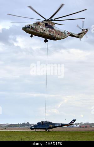 Transporthubschrauber Mi-26 T2B transportiert den Rumpf eines Kampfhubschraubers auf der externen Aufhängung. Schwerer Hubschrauber. Zur Kodifizierung von NAT Stockfoto