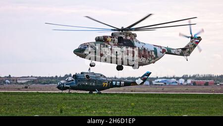 Transporthubschrauber Mi-26 T2B transportiert den Rumpf eines Kampfhubschraubers auf der externen Aufhängung. Schwerer Hubschrauber. Zur Kodifizierung von NAT Stockfoto