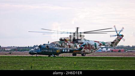 Transporthubschrauber Mi-26 T2B transportiert den Rumpf eines Kampfhubschraubers auf der externen Aufhängung. Schwerer Hubschrauber. Zur Kodifizierung von NAT Stockfoto