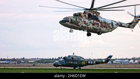 Transporthubschrauber Mi-26 T2B transportiert den Rumpf eines Kampfhubschraubers auf der externen Aufhängung. Schwerer Hubschrauber. Zur Kodifizierung von NAT Stockfoto