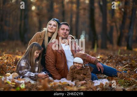 Die Familie hat eine tolle Picknickzeit in einem malerischen Eichenwald, der in Herbstfarben gekleidet ist Stockfoto