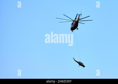 Transporthubschrauber Mi-26 T2B transportiert den Rumpf eines Kampfhubschraubers auf der externen Aufhängung. Schwerer Hubschrauber. Zur Kodifizierung von NAT Stockfoto